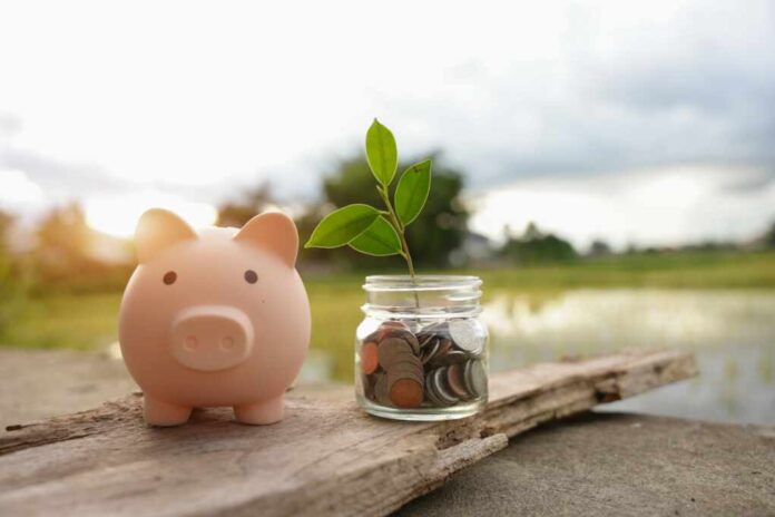 Saving,Money,By,Hand,Puting,Coins,In,Jug,Glass,On