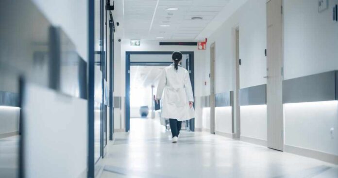 Female,Doctor,Walking,Away,In,An,Empty,Hospital,Hallway.,General