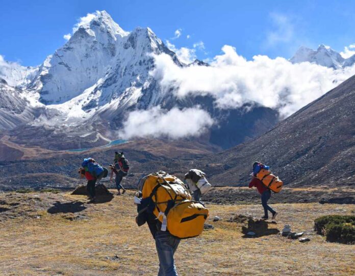 The,Adult,Sherpa,Porters,Carrying,Heavy,Backpacks,And,Sacks,In