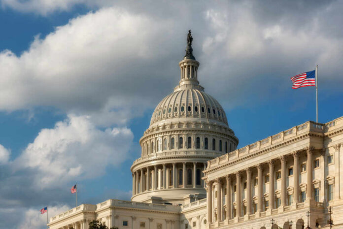 The U.S. Capitol building with a dome and American flag under a cloudy sky