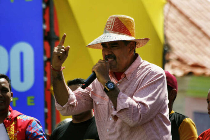A man in a straw hat passionately speaking into a microphone at a lively outdoor event