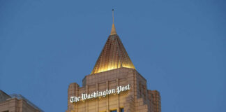 The top of a building featuring the sign of The Washington Post against a blue evening sky