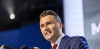 A man in a suit speaking at a podium during a conference