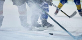 Ice hockey players competing on the rink with a puck in play