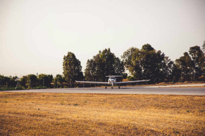 A small airplane on a runway surrounded by trees