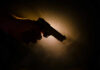 Silhouette of a hand holding a handgun against a dramatic light background