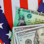 Energy Crisis GUTS Bigger Tax Refunds Close-up of U.S. currency with a backdrop of the American flag