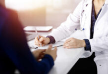 A doctor writing notes during a consultation with a patient