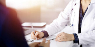 A doctor writing notes during a consultation with a patient