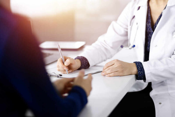 A doctor writing notes during a consultation with a patient