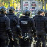 Group of police officers in riot gear facing away from the camera