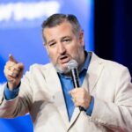 Senator EXPOSES Terrifying New Danger Inside America A man in a light suit passionately speaking into a microphone at a conference
