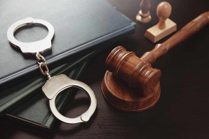 Handcuffs and a gavel on a desk with legal books