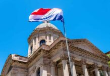 A national flag flying above a historic building under a clear blue sky