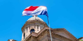 A national flag flying above a historic building under a clear blue sky