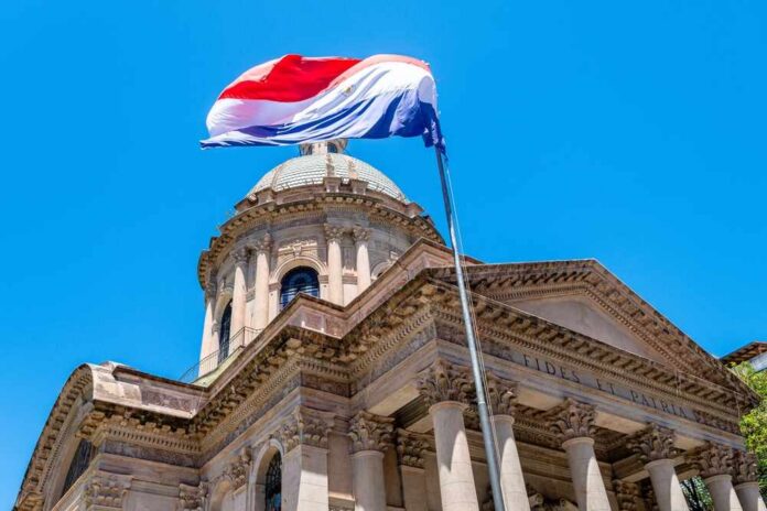 A national flag flying above a historic building under a clear blue sky