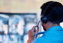 A surveillance operator wearing a headset while monitoring multiple screens