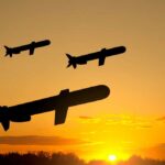 Silhouetted missiles flying against a sunset backdrop