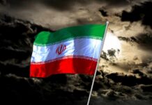 Iranian flag waving against a dark, cloudy sky