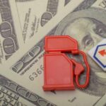Hormuz Chokehold Sparks $100 Oil Shock Red fuel pump toy next to hundred dollar bills