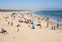 Crowded beach with people sunbathing and playing in the water