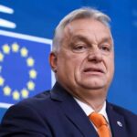 SHOCKING Russian Election Scheme Targets Hungary A political leader speaking at a press conference with the European Union flag in the background