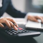Labour’s Stealth Tax Scheme EXPOSED — Outrageous! A business professional using a calculator while working on a laptop