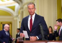 A male politician in a suit holding a notepad in a government building