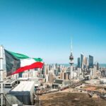 Kuwait flag waving over a city skyline with modern buildings