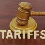 A wooden gavel next to the word 'TARIFFS' spelled out in wooden letters