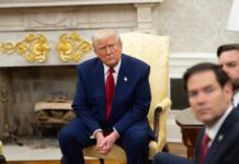 A group of political figures seated in a formal setting, with one individual looking contemplative