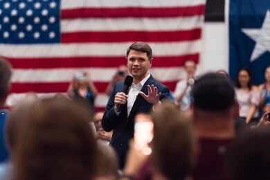 A speaker addressing an audience in front of an American flag