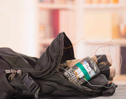 A backpack containing a mobile phone and wires, suggesting a suspicious setup