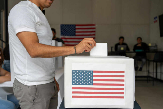 Person casting a vote into a ballot box with an American flag