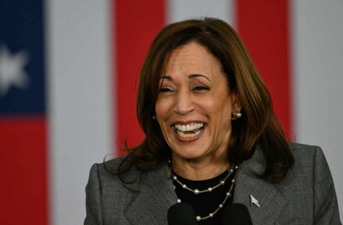 shutterstock2535154433jpg A woman smiling while speaking at a podium with an American flag backdrop