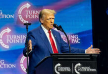 A man in a blue suit speaking at a podium with a microphone