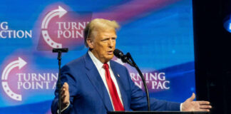A man in a blue suit speaking at a podium with a microphone