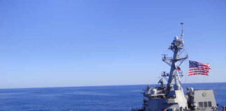 A naval destroyer sailing in the ocean with an American flag
