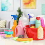 A variety of cleaning supplies arranged around a red bucket