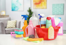 A variety of cleaning supplies arranged around a red bucket