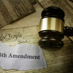 A gavel resting on a document labeled '25th Amendment' surrounded by historical papers