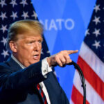 A man delivering a speech with American flags in the background