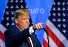 A man delivering a speech with American flags in the background