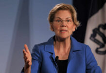 A woman in a blue blazer speaking passionately at a podium