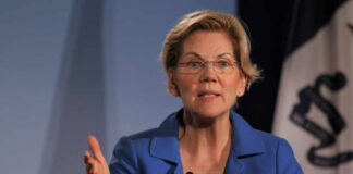 A woman in a blue blazer speaking passionately at a podium