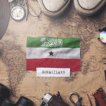 Somaliland flag placed on a vintage map surrounded by travel items