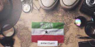 Somaliland flag placed on a vintage map surrounded by travel items