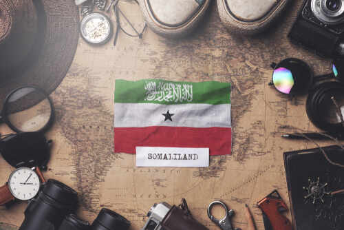 Somaliland flag placed on a vintage map surrounded by travel items
