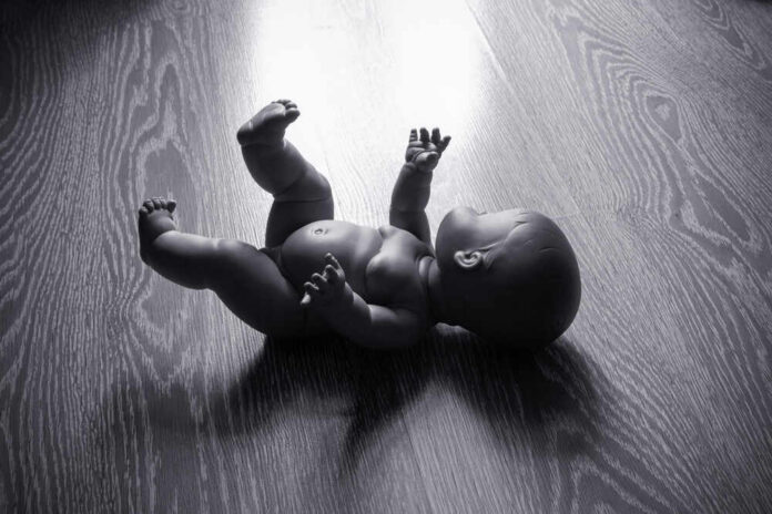 A black and white image of a doll lying on a wooden floor