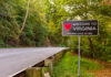 Welcome sign for Virginia along a tree-lined road